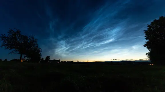 Dark evening sky with glowing noctilucent clouds near Schönau-Berzdorf (Saxony).