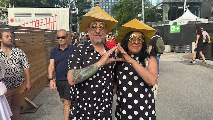 Two people wearing polka dots and a tricorn hat form a triangle, each holding hands.