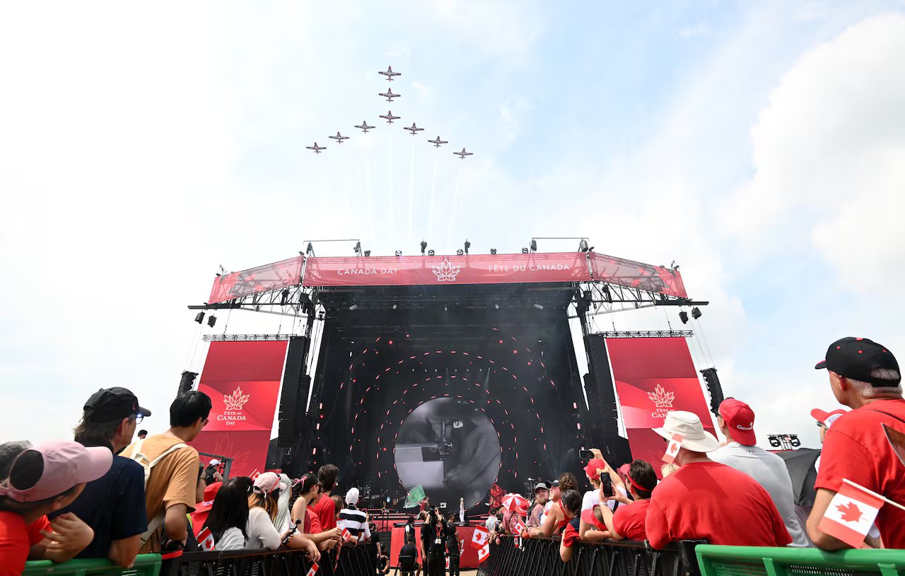 An aerobatic jet team flies over the crowd in a peace sign.