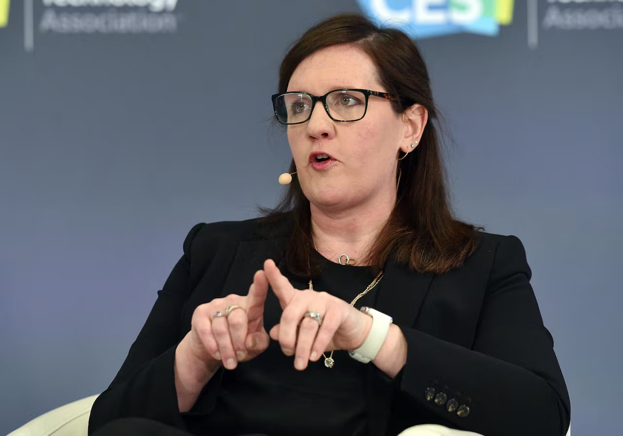 A brunette with glasses speaks while sitting.