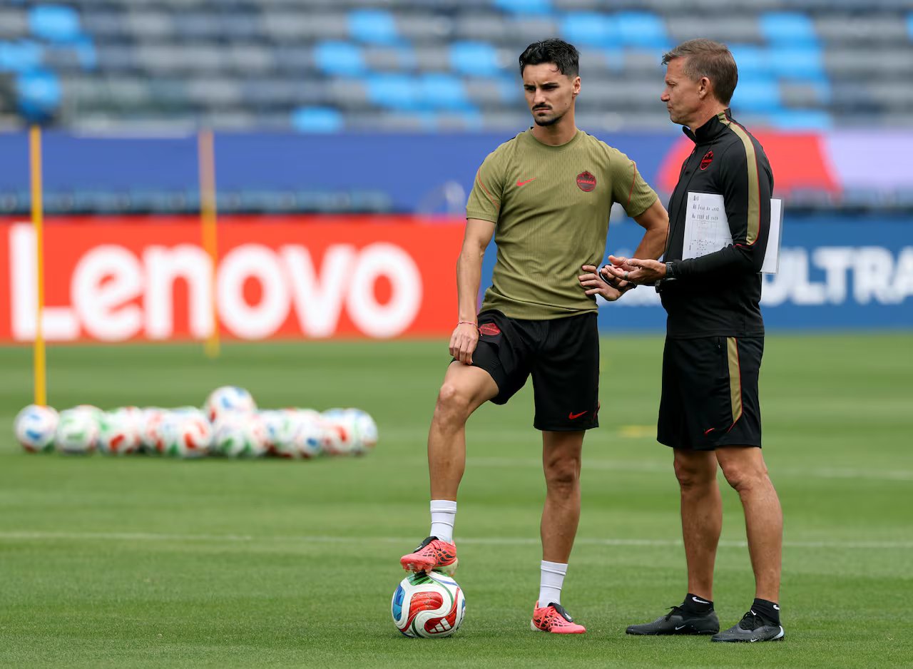 A football player and a coach are talking on the field.