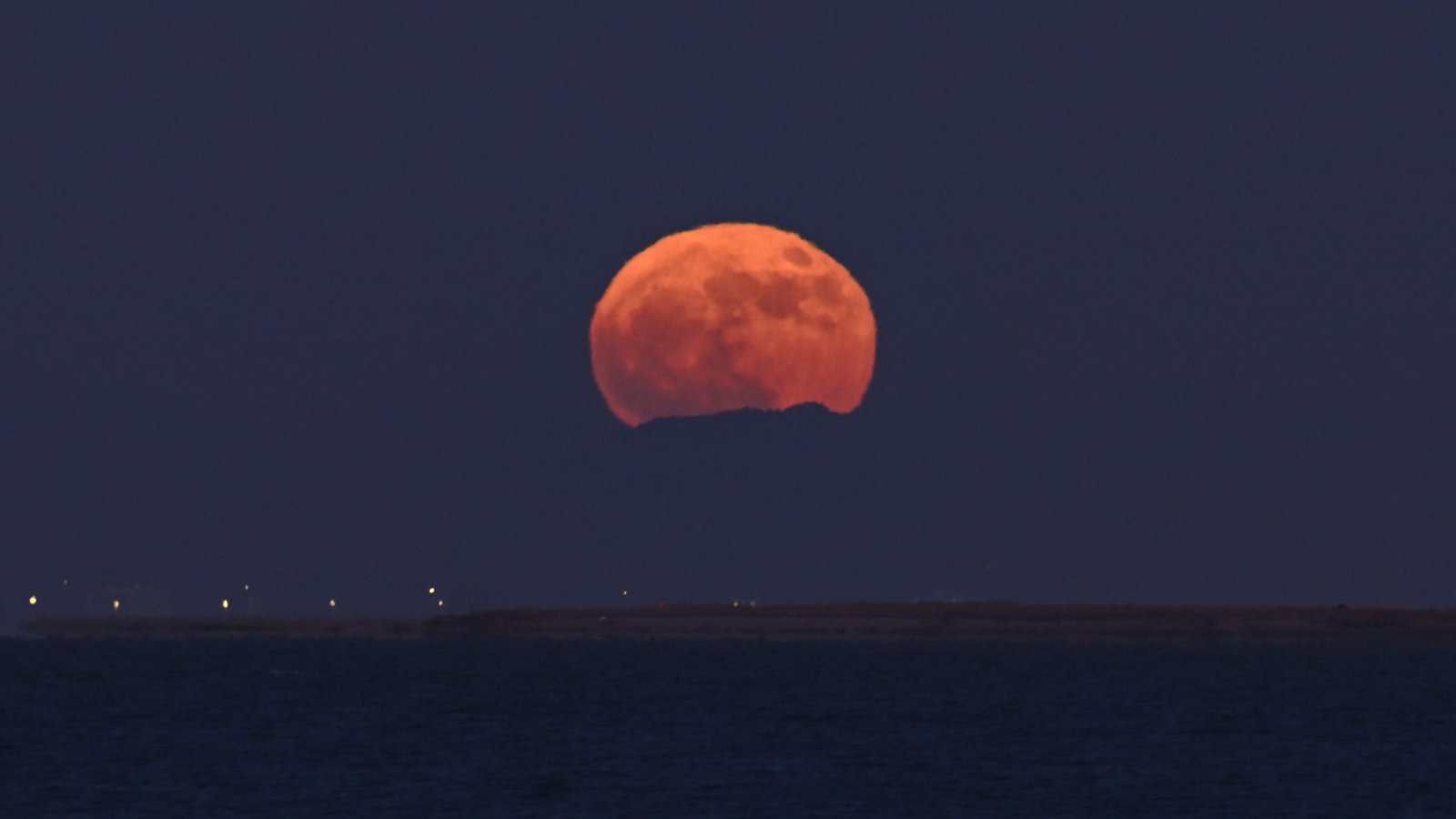 June's Strawberry Moon will be a welcome treat for skywatchers around the world. Here are our favorite photos 25 a large strawberry-red moon rises over a large body of water.