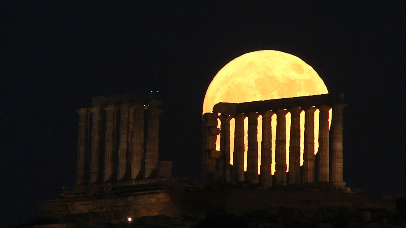 June's Strawberry Moon will be a welcome treat for skywatchers around the world. Here are our favorite photos 29 a large yellow moon appears behind the stone pillars.