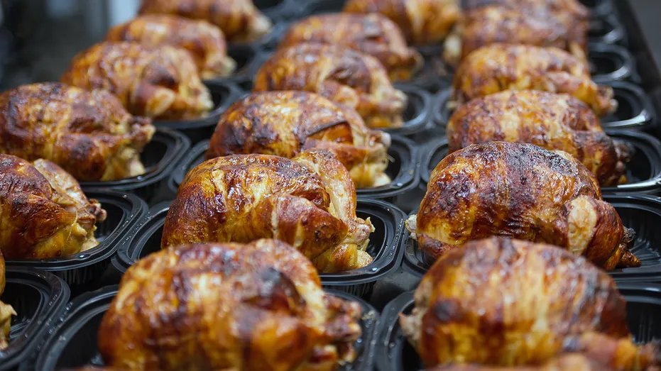Sam's Club Rotisserie Chicken Beats Costco, Consumer Reports Says 14 Rows of cooked rotisserie chickens in black plastic trays at a grocery store.