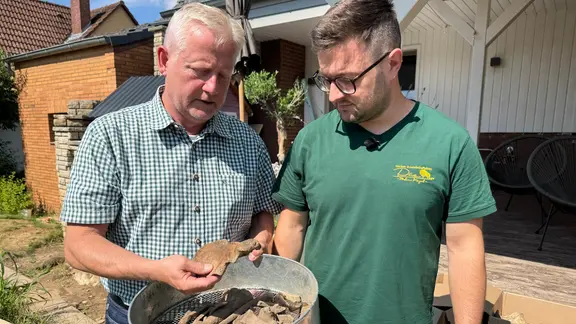 Two men look at old bones.
