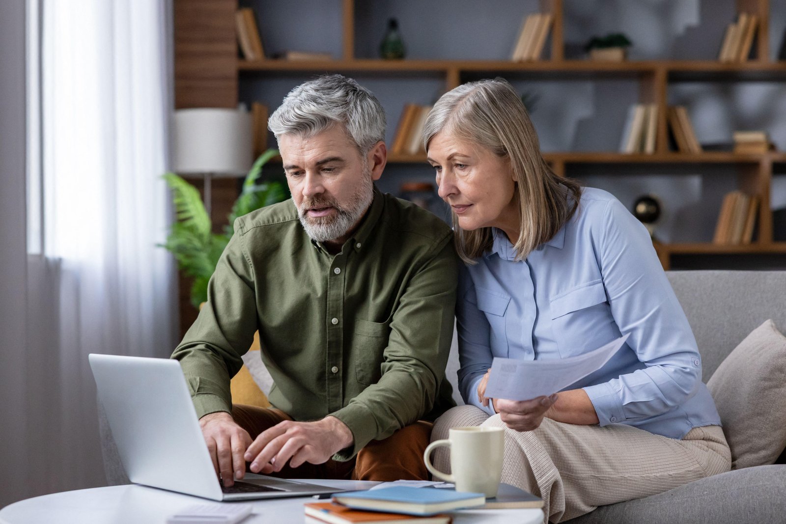 Elderly couple sitting on sofa and looking at laptop