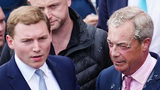 Nigel Farage: MP quits in right-wing bombshell and says he'll run again 17 George Cottrell, wearing a blue tie, was with Farage when a woman threw a milkshake on him during the 2024 election campaign.