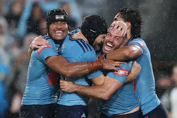 Blues defender James Tedesco is surrounded by a crowd of teammates after scoring the winning try in the dying moments of the State of Origin I match in Sydney in May. 