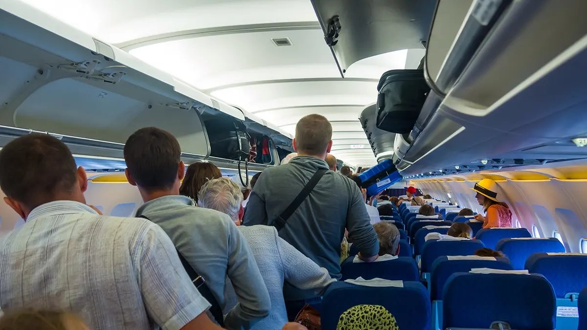 People are standing to get off the plane.