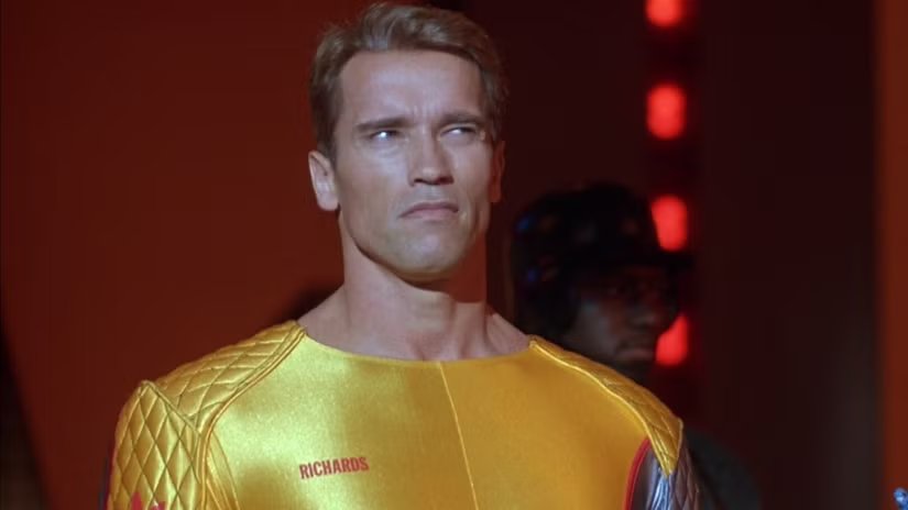 Arnold Schwarzenegger as Ben Richards wearing a yellow tracksuit in The Running Man (1987)