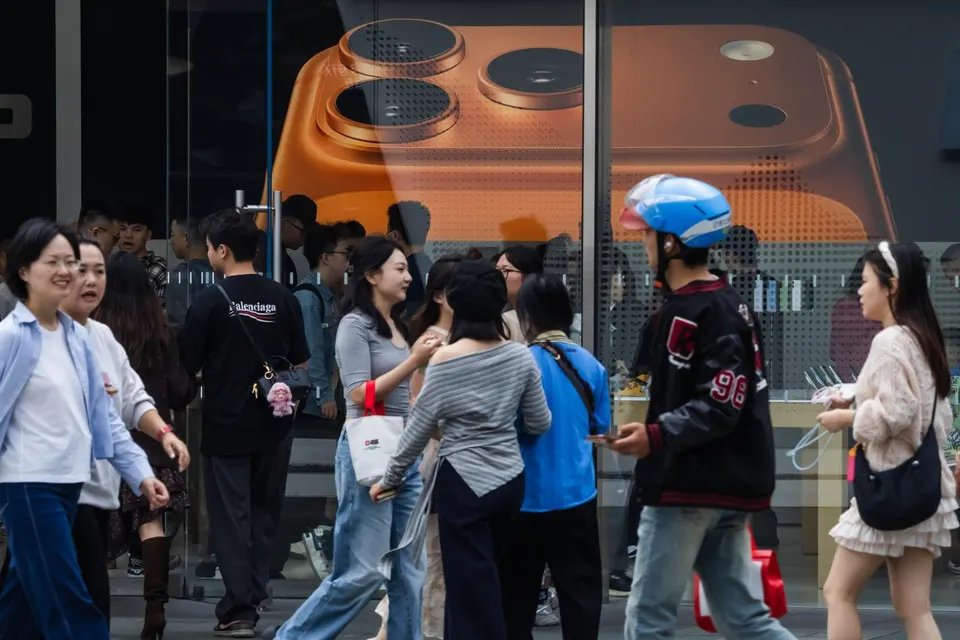 A crowd walks past an Apple Store with an iPhone 17 Pro poster in Chengdu