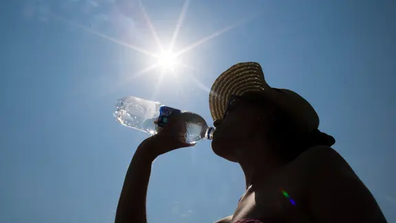 A woman drinks water from a bottle.