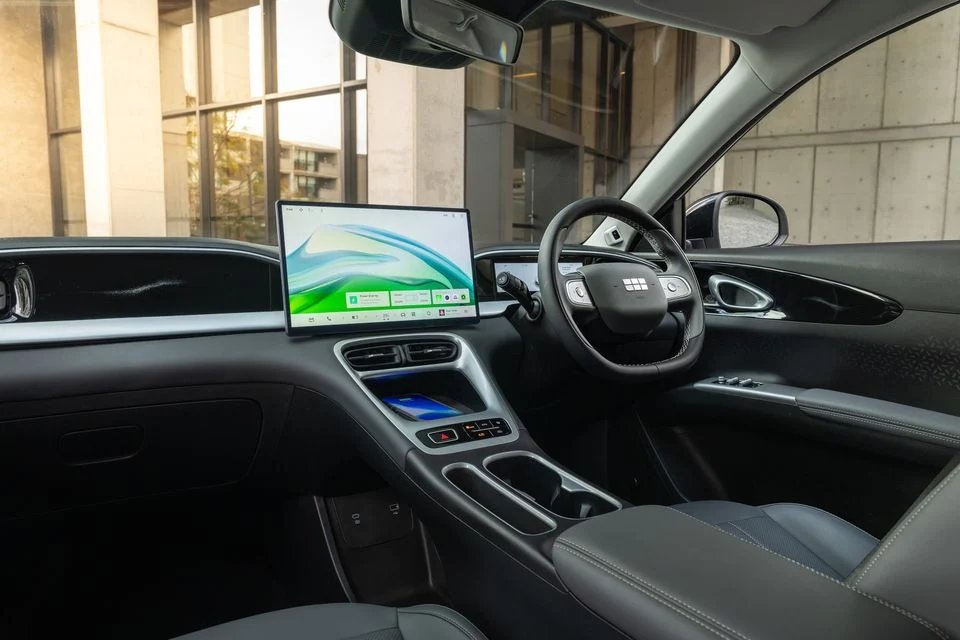 Geely EX2 interior with large landscape touchscreen infotainment display, steering wheel, center console and front seats.