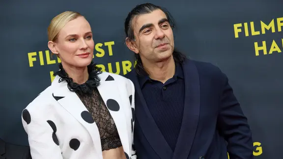 Diane Kruger and Fatih Akin pose in front of a wall with 