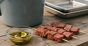 Homemade marinated meat skewers with lemon oil and herb marinade on a wooden board