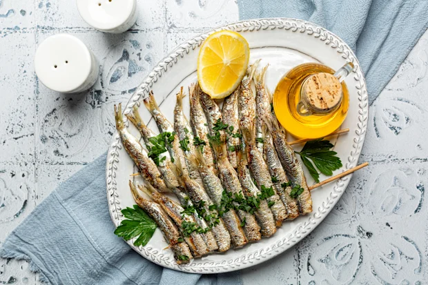 Sardine shortage: With sardines missing from shelves, what are the best canned fish? 21 f Grilled sardine skewers on a white plate with lemon and olive oil. Mediterranean food.