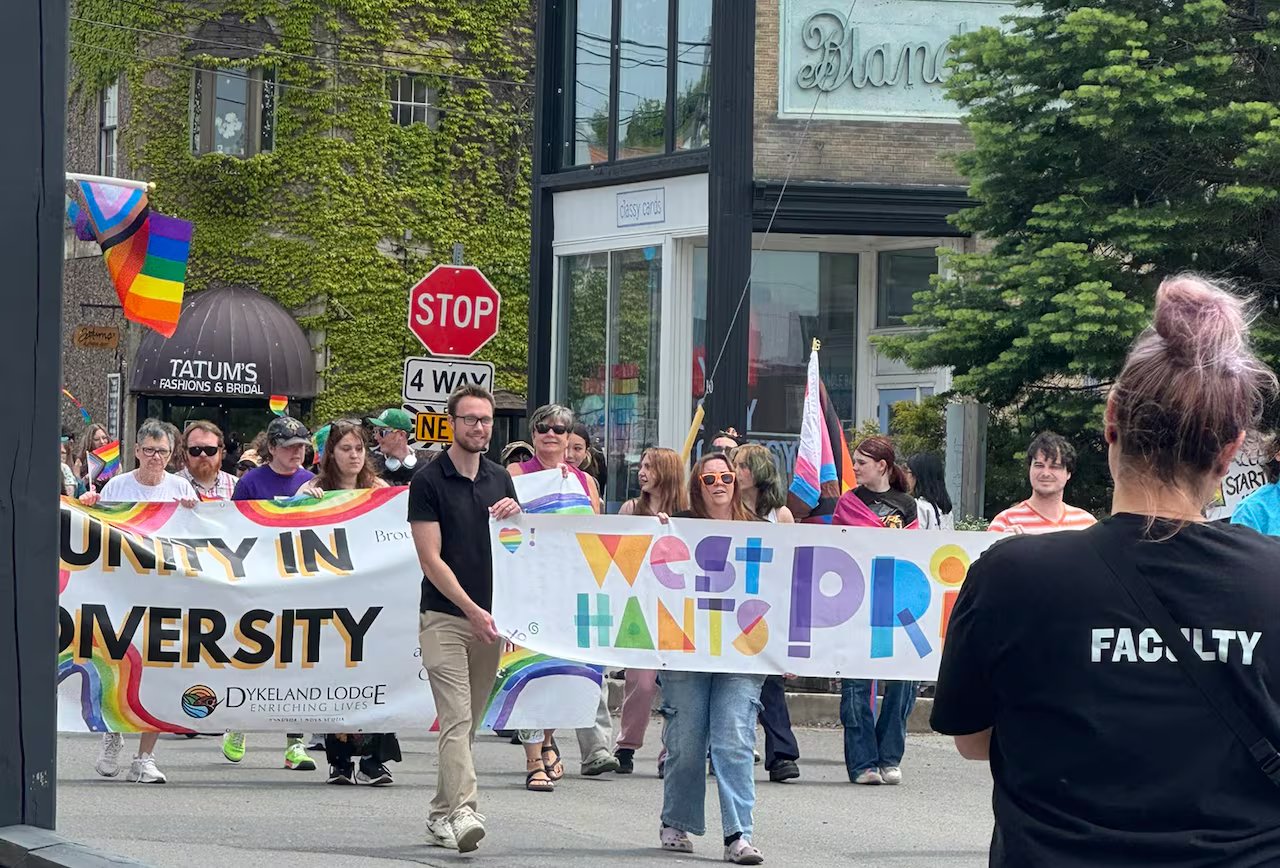A group of people go to the West Hants Pride Parade. One sign says 