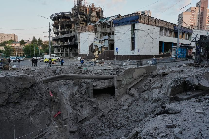 Debris surrounds a missile crater in the foreground of a building after Russia's missile strike on Kyiv on Sunday.