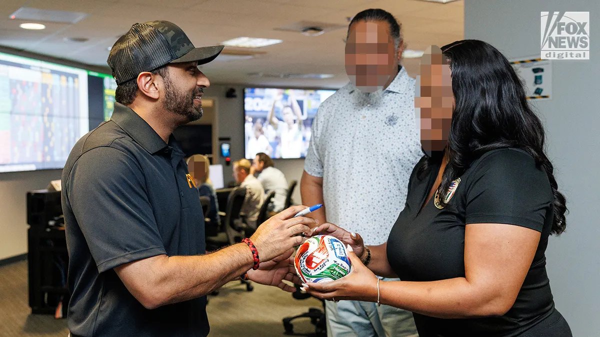 Cash Patel signs a football.