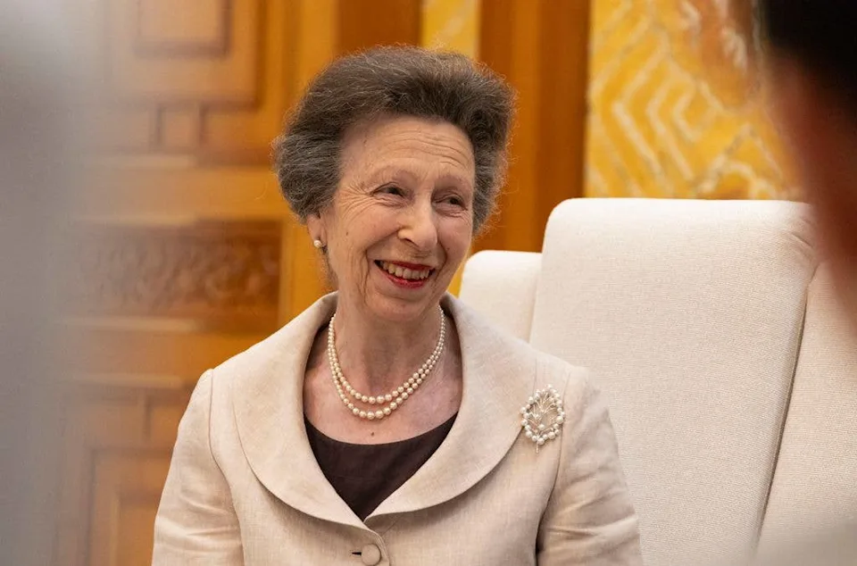 Princess Anne in a cream jacket and red lipstick smiles