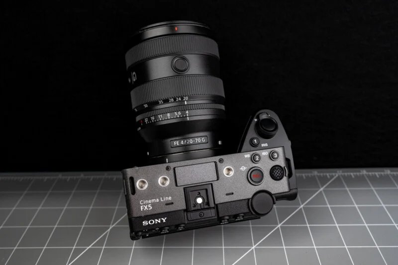 Sony FX5 has a new sensor, open shutter, internal RAW and more 25 Sony Cinema Line FX3 camera with FE 4/20-70 G lens placed on a gray cutting mat, top view against a black background.