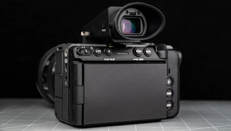 Sony FX5 has a new sensor, open shutter, internal RAW and more 28 A digital camera with a closed flip-up screen is shown from behind, sitting on a grid-patterned surface against a black background.