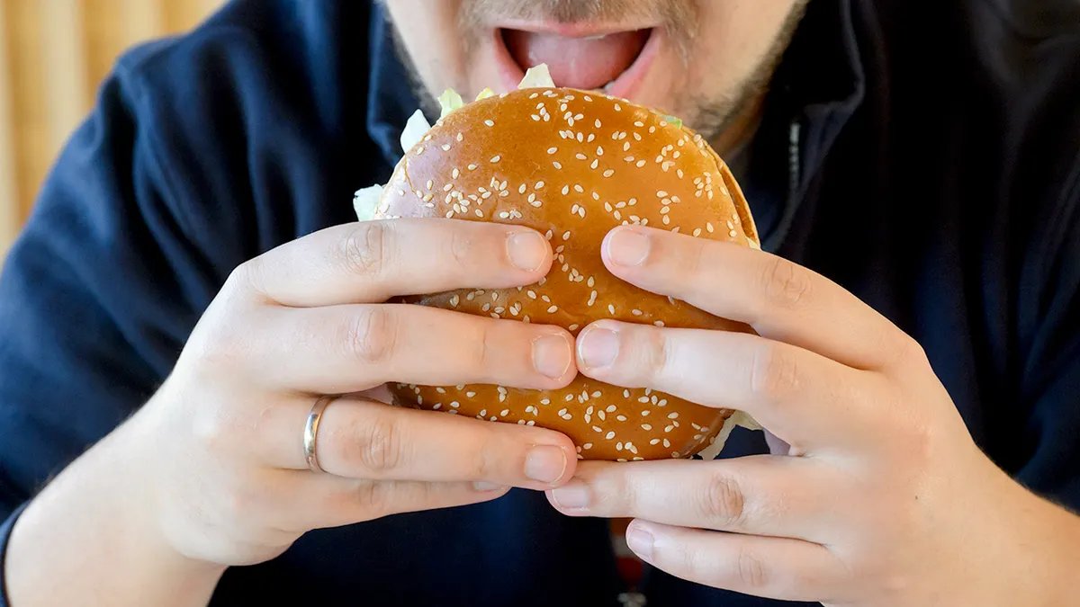 A man prepares to take a bite of a Burger King Whopper.
