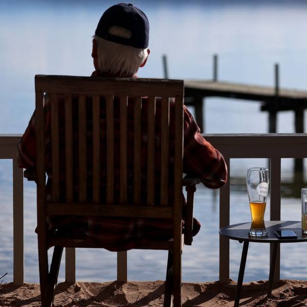 A traveler sits in the sun in a beer garden on Lake Ammersee, with a beer standing next to him.