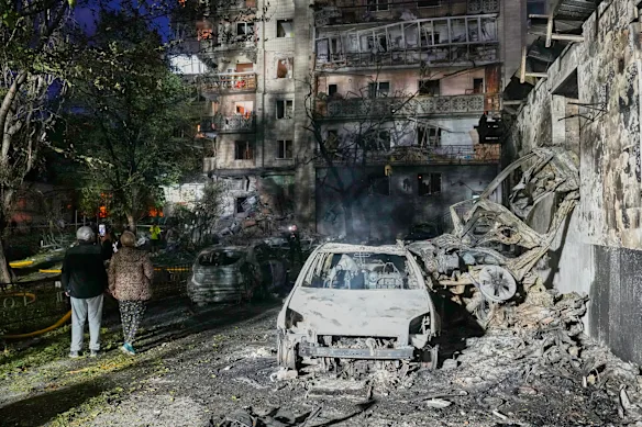 Residents walk among the rubble of a Russian missile strike on Kyiv on Sunday.