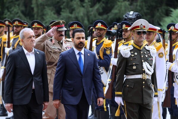 In this photo released by the Office of the President of Iran, Iraqi Prime Minister Ali al-Zaidi (center) inspects a guard of honor as he is greeted by Iranian President Masoud Pezeshkian (left) during an official welcoming ceremony in Tehran, Iran, Thursday, July 22, 2026. (Office of the Iranian President via AP)