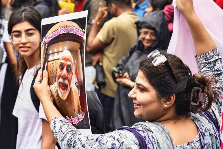 A protester holds a poster with a portrait of Indian Prime Minister Narendra Modi and text loosely translated as 
