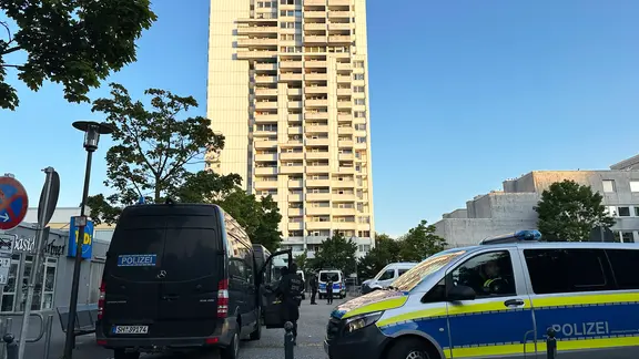 Police cars are parked in front of a white high-rise building in the Mettenhof district of Kiel.