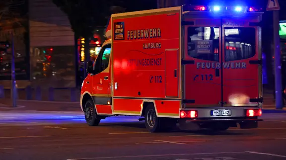 Police and fire departments suspect mixed intoxication. (Symbolic image) | painting A Hamburg fire department ambulance arrives at the scene with its blue lights flashing.