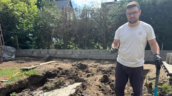 A man stands in a dug up garden.