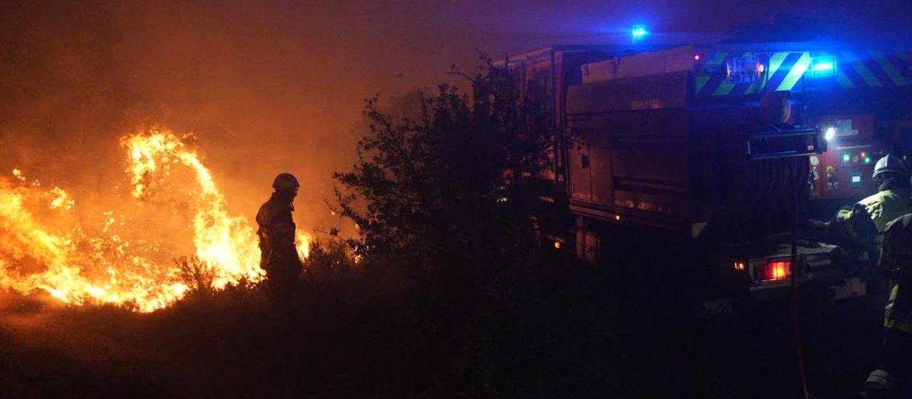 A fire engine and fire brigade extinguish a forest fire near La Fare in southern France.