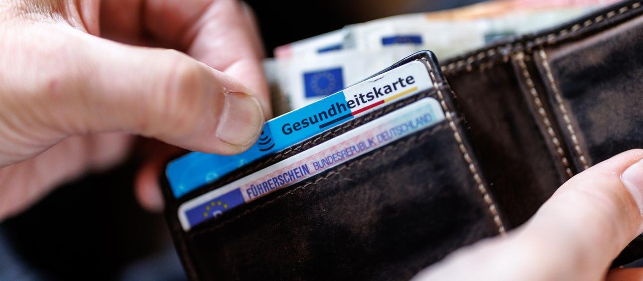 The man takes out a medical card from his wallet. | photo alliance / dpa The man takes out a medical card from his wallet.