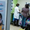 ICE shared Medicaid data with Palantir that it shouldn't have: NPR 16 The patient care room is photographed from the outside. A Spanish poster is visible and a doctor in a white coat is seen caring for a child on an examination table.