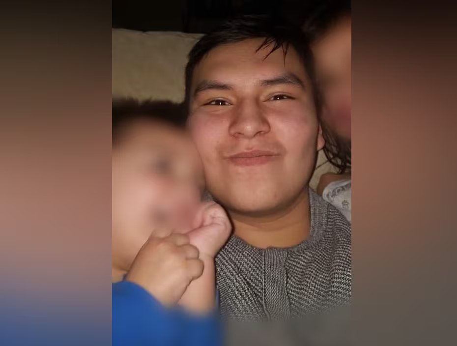 A man smiles at the camera, next to him are two children with blurred faces.