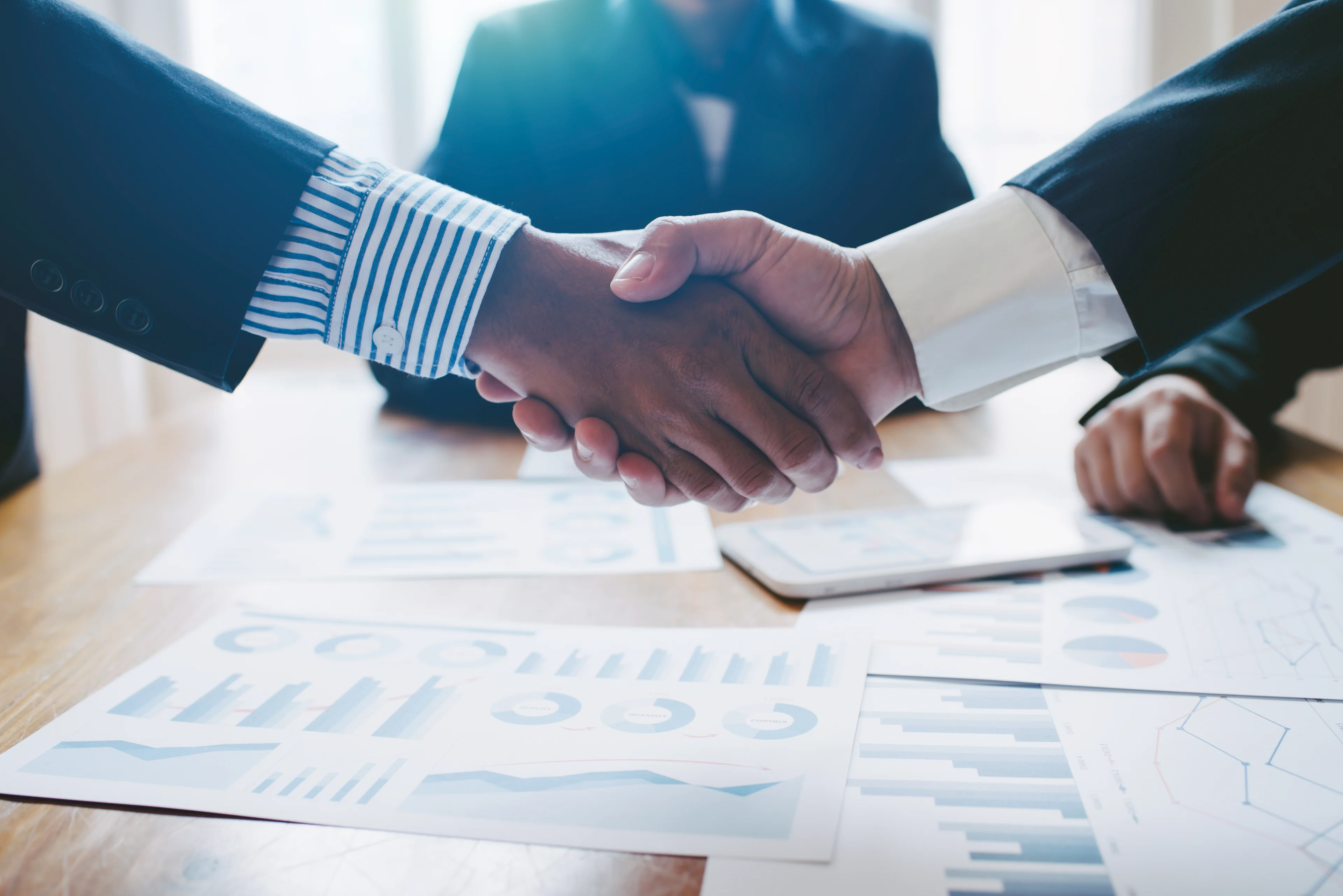 JP Morgan calls Elon Musk's potential merger with SpaceX and Tesla "strategically consistent" 15 Two people shake hands at a board meeting.