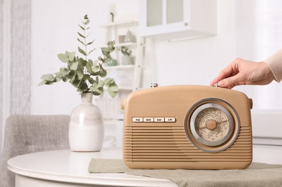 woman turns the volume knob on a radio indoors, close-up. space for text