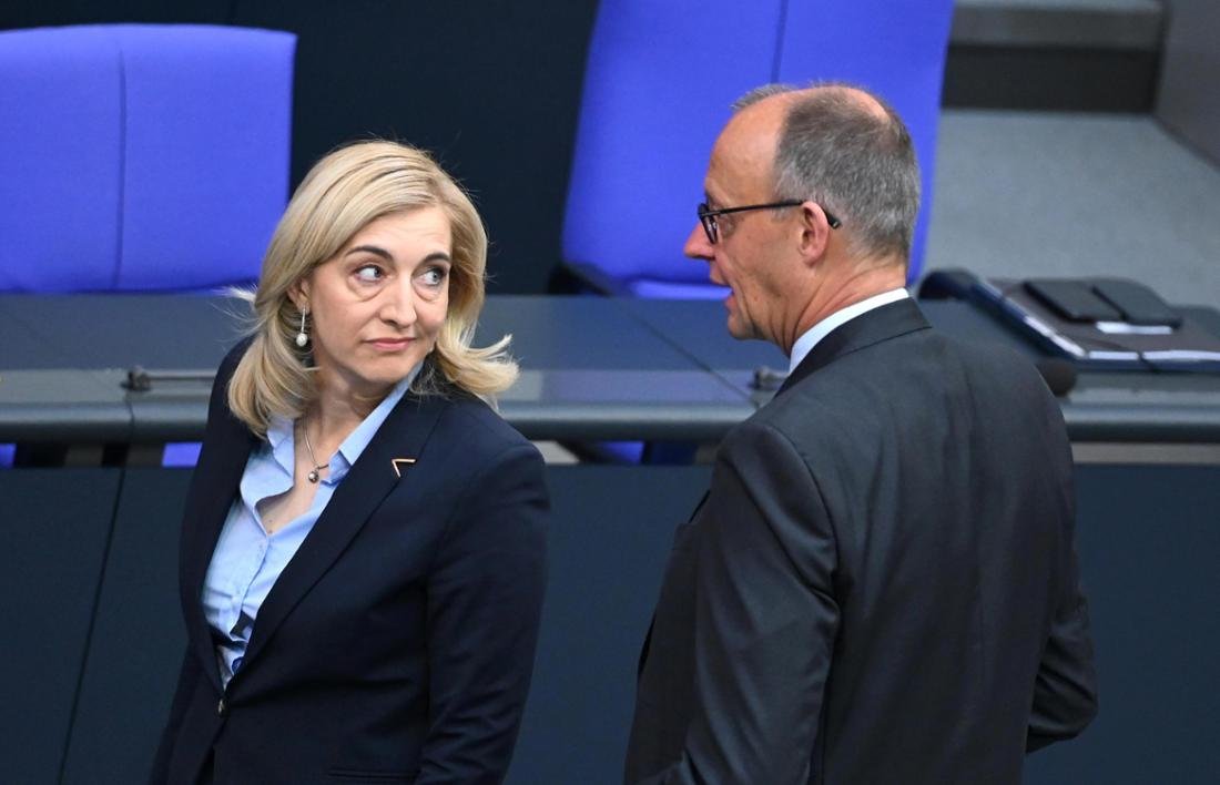 Nina Warken, Federal Minister of Health, and Federal Chancellor Friedrich Merz talk to each other in the plenary hall of the Bundestag.