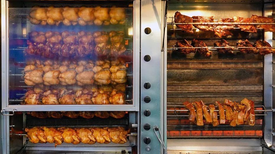 Sam's Club Rotisserie Chicken Beats Costco, Consumer Reports Says 13 Rotisserie chickens are roasted on a spit in a commercial oven at a grocery store.