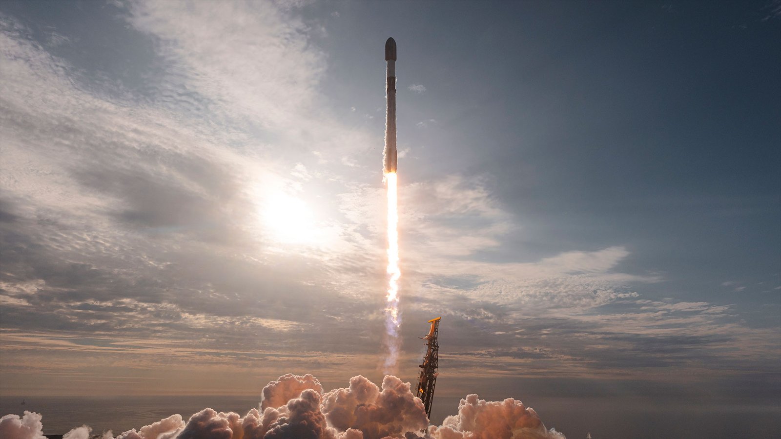 pre-twilight rocket launch into partly cloudy skies