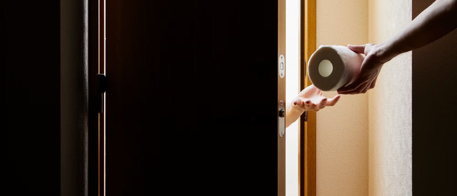 A hand passes a roll of toilet paper through a crack in the door into a dark room. The painting depicts the moment of surrender when light from outside enters the room. The focus is on the act of giving and receiving. A hand passes a roll of toilet paper through a crack in the door into a dark room. The painting depicts the moment of surrender when light from outside enters the room. The focus is on the act of giving and receiving.
