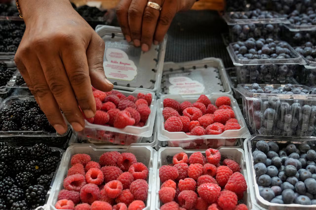 Hands arrange berries at a stand in Cleveland, July 2025.