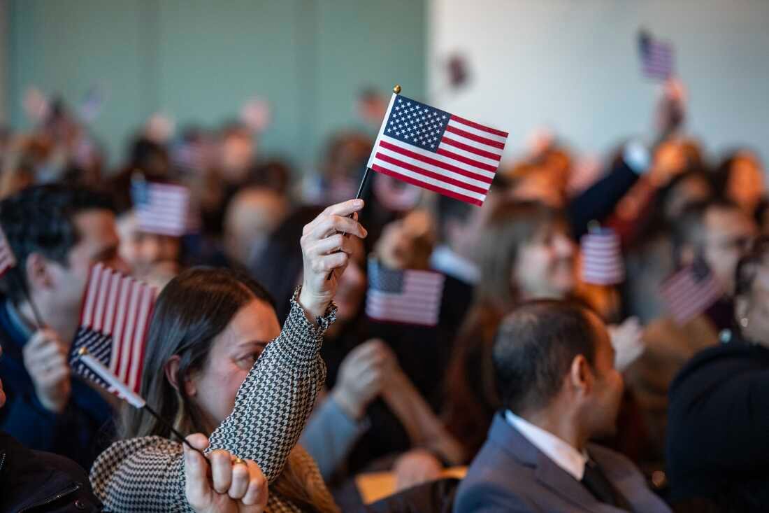 People wave U.S. flags to celebrate becoming U.S. citizens after taking the Oath of Allegiance during a naturalization ceremony in Boston in January 2025.