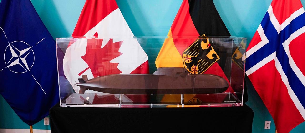 Behind the submarine model you can see the flags of the North Atlantic Treaty Organization (NATO), Canada, Germany and Norway. | Justin Tang/The Canadian Press/A Behind the submarine model you can see the flags of the North Atlantic Treaty Organization (NATO), Canada, Germany and Norway.