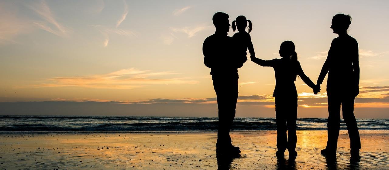 Silhouettes of parents with two daughters on the beach