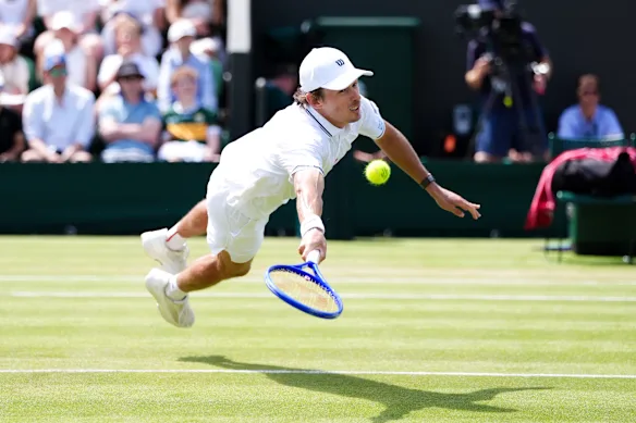Alex de Minaur takes to the air and hits a volley during his four-set win over Zak Svaida.
