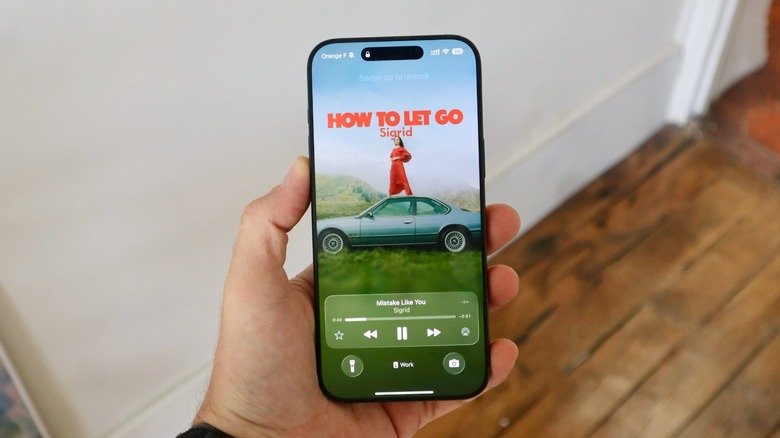 Hand holding iPhone with animated Apple Music cover on lock screen